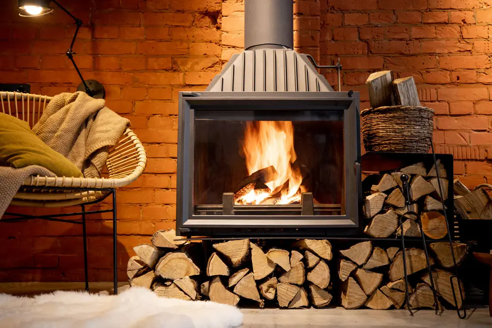 Firewood neatly stacked next to a Queenstown holiday home fireplace overseen by The Butler